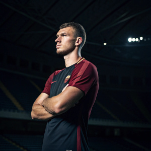 Edin Dzeko, footballer, posing with a serious expression. Dark stadium background