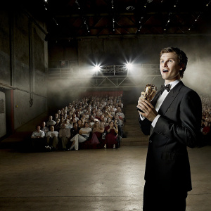 Ansel Elgort accepting an award at the MTV Movie Awards. Wearing a suit. Crowded venue with flashing lights