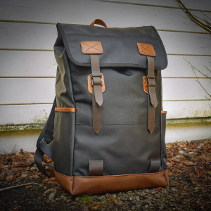 EastPak London backpack in the spotlight. Sleek modern design, black body with brown accents, featuring multiple straps and leather-like details.