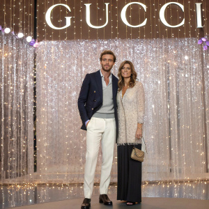 Claudio Marchisio and Roberta Sinopoli attending a Gucci fashion show. Standing in front of an extravagant, sparkling backdrop adorned with the Gucci logo.