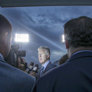 Pete Carroll, coach of the Seattle Seahawks, in a formal suit, speaking at a press conference. Crowd of journalists and photographers