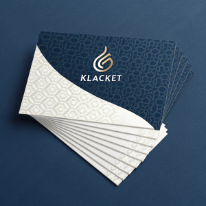 A sleek business card design for a media production company called Klacket. The card features a dark blue background and a white card with modern Arabic branding and contact details. The logo is a sophisticated abstract shape. The cards are creatively laid out.