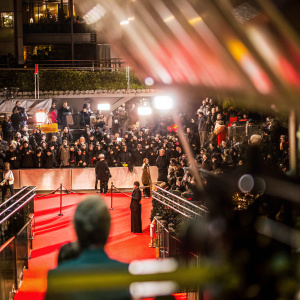 Jeffrey Tambor and Kasia Ostlun at the Golden Globe Awards. Crowded red carpet with flashing cameras and blurred audience.