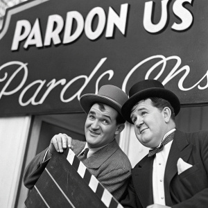 Vintage film advertisement for 'Pardon Us'. Starring Stan Laurel and Oliver Hardy. Black and white, classic movie poster style.