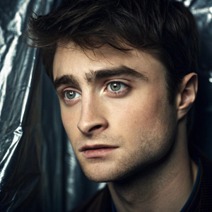 Close-up of Daniel Radcliffe's face. Focus on his eyes and detailed facial features. Shot on a glossy metallic backdrop.