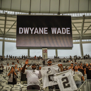 Dwyane Wade's jersey retirement ceremony. Crowded stadium, large screen showing Wade's highlights.