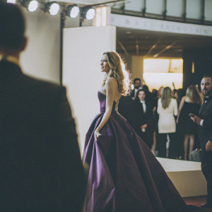Amber Heard, elegant and poised, in a vibrant purple evening gown at a high-profile awards show. The crowd is bustling behind her.