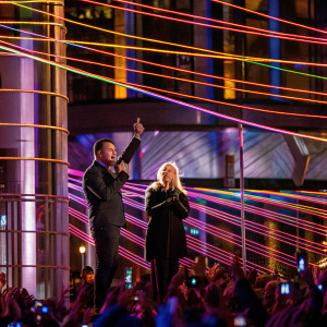 Christina Aguilera and Carson Daly performing live at the iHeartRadio Music Awards. Stage lights, crowd in background