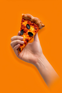 the hand holding the pizza slice over the edge