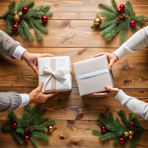 dos cajas blancas pequeñas siendo entregándose por dos personas diferentes mirandose entre si, en navidad con vista cenital mostrando solo las cajas