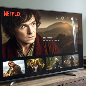 Netflix screen showing 'The Hobbit: An Unexpected Journey' movie poster. Character's face prominently displayed, surrounded by thumbnails of other Netflix titles.