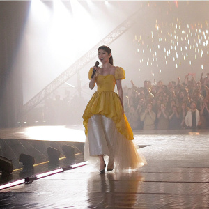 IU, Korean idol, in a yellow and white off-shoulder gown. Performing at Seoul Music Awards.