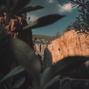 Digital art featuring rugged cliffs and greenery. Assassin's Creed Valhalla: Dawn of Ragnarok. Clear blue skies and wispy clouds. Realistic lighting and textures.