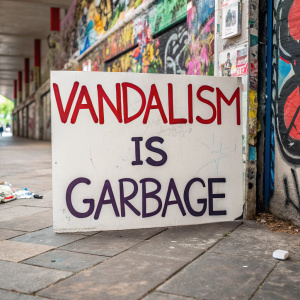 Anti-vandalism poster featuring bold text 'Vandalism is Garbage'. Colorful, graffiti-filled background.