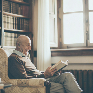 Norman Lovett, an older gentleman, with a bald head and a balding hairline. Sitting in a cozy library.