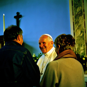A candid photo of Pope John Paul II smiling warmly while conversing with a man and a woman in a cozy, church setting.