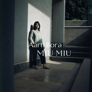 A minimalist design featuring Aarti Bora. Modern font, sleek 'MIU MIU' logo on a clean white backdrop
