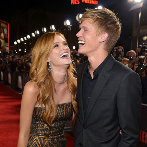 Bella Thorne and Tristan Klier laughing on the set of a movie premiere. Crowded event with flashing cameras.