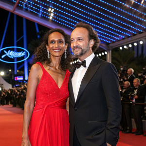 Karine Silla and Vincent Perez at Cannes Film Festival premiere. Lavish red carpet, blue neon lights in background.