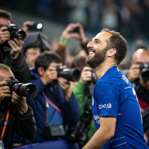 Gonzalo Higuain, beaming with joy, dressed in blue jersey, surrounded by fans eager to capture a moment with their cameras.