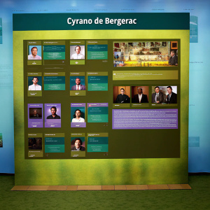 Website layout showcasing 'Cyrano de Bergerac'. Modern, sleek design with dark background and gold highlights. Features cast photos, role assignments, and stage configuration details.