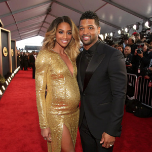 Ciara, wearing a gold sequined dress, and Russell Wilson in a black suit. They pose on the bustling GRAMMY red carpet. Crowds of fans and paparazzi in the background.