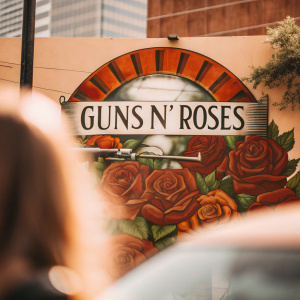 A vibrant graffiti mural featuring the iconic Guns N' Roses logo. Painted on a city wall, the design incorporates bold colors and realistic rose details