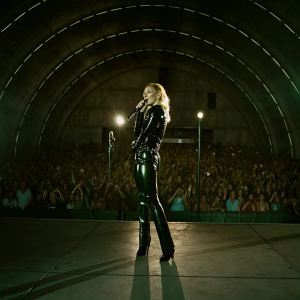Christina Aguilera performs at the Hollywood Bowl. Wearing a shiny black outfit. Crowd visible in the background