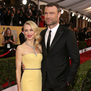Liev Schreiber and Naomi Watts at a glitzy awards show. Liev in a sleek black suit, Naomi in a striking yellow dress.