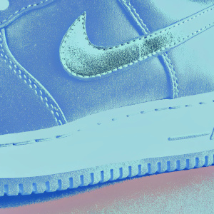 Brown suede Nike Air Force 1 sneakers. Shiny silver swoosh logo. Clean, minimalist look. Sole with visible stitching. White midsole. Stylish streetwear