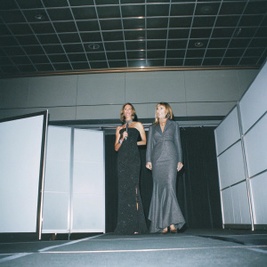 Giuliana Rancic and Debbie Stang, elegantly dressed, at the annual Women in Cable Telecommunications Gala. Standing on stage with a modern, sleek backdrop.