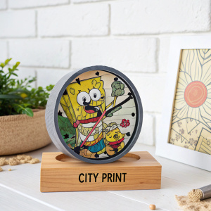 Spongebob Squarepants characters featured on a quirky puzzle clock. Clock sits on a wooden platform with City Print logo. The scene is against a minimalist white backdrop.