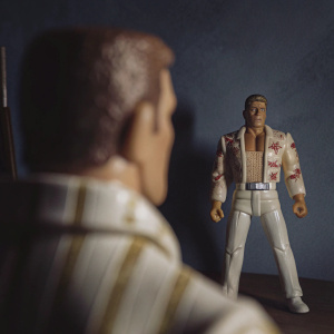 Close-up shot of a Duke Nukem action figure, standing confidently in a dark studio setting, showcasing his muscular build and attire.