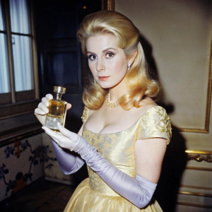young Catherine Deneuve from the film Belle De Jour with a bottle of perfume in hand in beautiful dinner dress