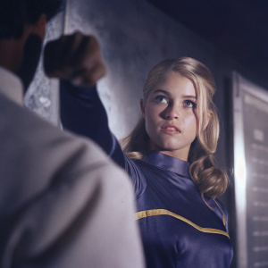 Saturn Girl from the Legion of Super-Heroes. Blonde hair, determined expression, in a blue costume with yellow accents. Scene from modern comic book.