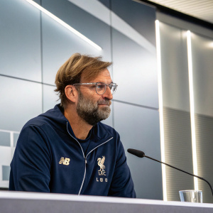 Jurgen Klopp, bearded and bespectacled, at a press conference. Wearing a navy Adidas jacket. Corporate backdrop, sleek and modern