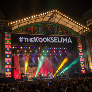 Promotional image for The Kooks concert in Lima. Colorful stage setup, vibrant lighting, hashtag #THEKOOKSELIMA