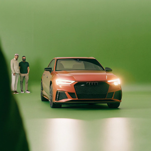 Red Audi RS3 Sportback showcased at auto show. Sleek design and aggressive front grille. Bright lights highlighting car contours. People in the background