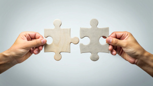 Two hands joining together two jigsaw puzzles stock photo