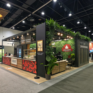 La Marzocco's sleek trade show booth at the annual coffee expo. Filled with vibrant displays, inviting decor, and greenery.