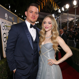 Channing Tatum in a tailored navy suit, Amanda Seyfried in a flowing silver gown. Standing together at the Golden Globe Awards, flashing lights and excited crowd in background.