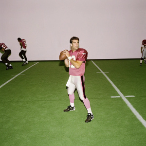Kurt Warner, serious demeanor, in New York Giants jersey, preparing to throw the ball during an intense NFL game.
