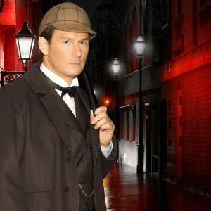 A CGI rendering of a man resembling Sherlock Holmes. He is wearing a Victorian era suit with a deerstalker hat. Serious expression. The background is a dimly lit, foggy London street at night.