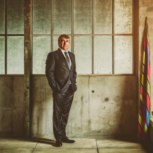 Joan Laporta, FC Barcelona president, in black suit and tie. Stands before a stark white background at official club event.