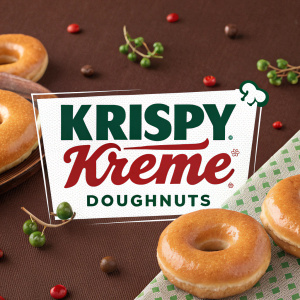 Homepage of Krispy Kreme Doughnuts in Spanish. Prominent banner featuring a glazed donut. Green and red accents. Rich brown background.