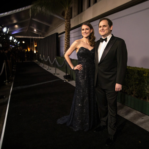 Michael Stuhlbarg with his partner at an awards ceremony. Dimly lit, black carpet.