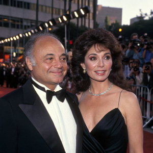 Burt Young and Lisa Scuteri attending the Hollywood premiere. Wearing formal attire. Crowds of photographers and fans in the background.