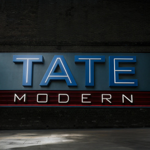 The Tate Modern's sleek logo with 'TATE' in bold, large font and 'MODERN' in a smaller, subtle script. Set against a vibrant neon backdrop.
