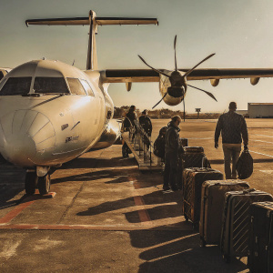 An ATR-42-500 aircraft, painted in Czech Airlines livery, sits on a tarmac under clear blue skies. Passengers boarding