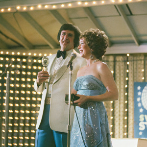 Alan Arkin and Suzanne Newlander Arkin at a star-studded gala. Dressed in elegant evening wear. On stage, accepting an award.